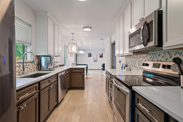 kitchen featuring decorative light fixtures, tasteful backsplash, sink, appliances with stainless steel finishes, and white cabinets