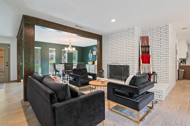 living room with a fireplace, a chandelier, beam ceiling, and light hardwood / wood-style floors