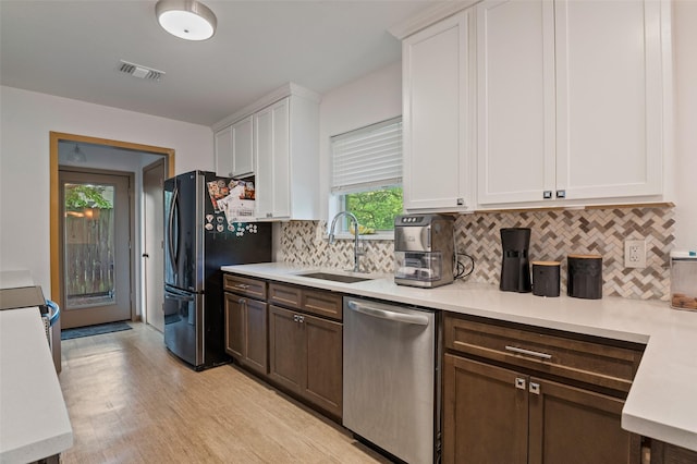 kitchen with white cabinetry, stainless steel appliances, backsplash, light hardwood / wood-style flooring, and sink