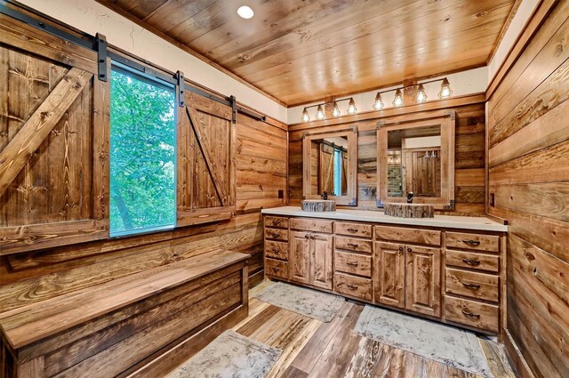 interior space with a barn door, wood ceiling, a wealth of natural light, and light hardwood / wood-style flooring