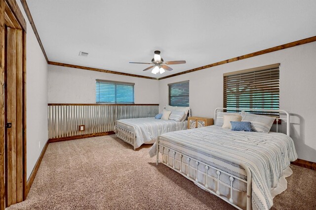 carpeted bedroom with ceiling fan, crown molding, and wooden walls