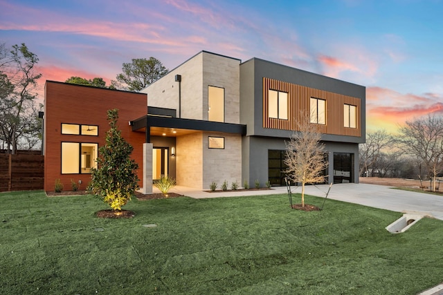 contemporary house featuring a garage, concrete driveway, and a front lawn