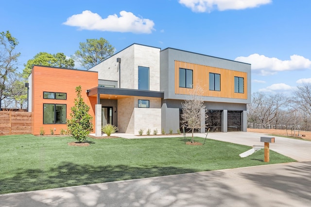 contemporary house featuring a garage, concrete driveway, a front yard, and fence