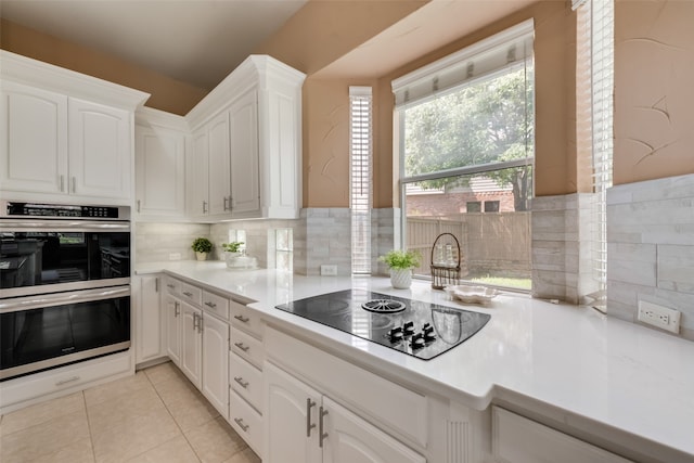 kitchen featuring light tile patterned flooring, white cabinetry, double oven, and black electric cooktop