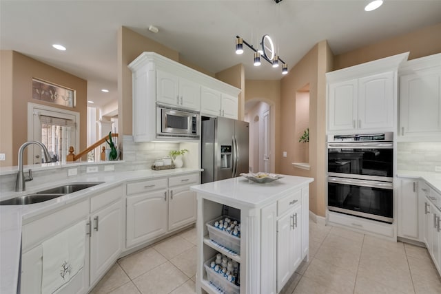 kitchen with decorative backsplash, sink, white cabinets, and appliances with stainless steel finishes