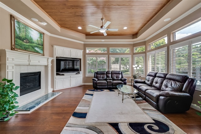 living room with dark hardwood / wood-style flooring, a raised ceiling, ceiling fan, a tile fireplace, and wooden ceiling