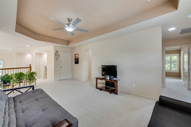 living room featuring a tray ceiling, ceiling fan, and light colored carpet