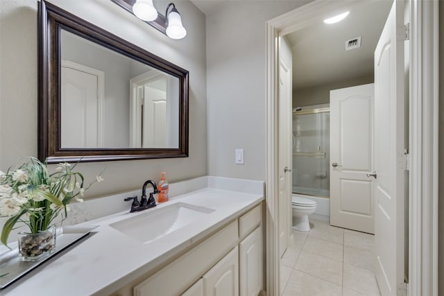 full bathroom featuring tile patterned flooring, vanity, combined bath / shower with glass door, and toilet