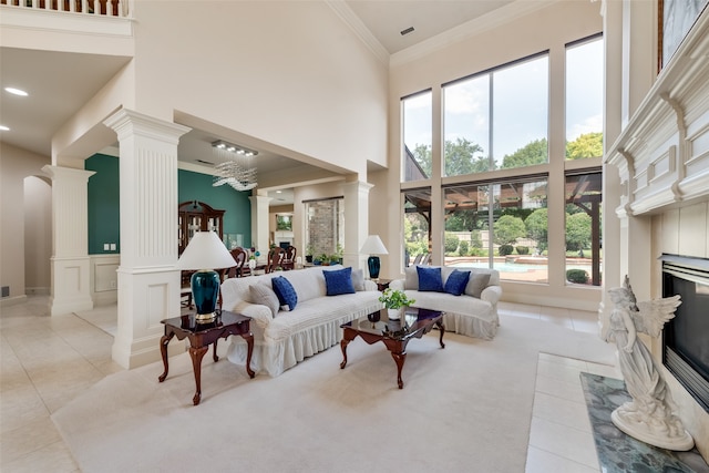 carpeted living room with a high end fireplace, a high ceiling, decorative columns, and crown molding