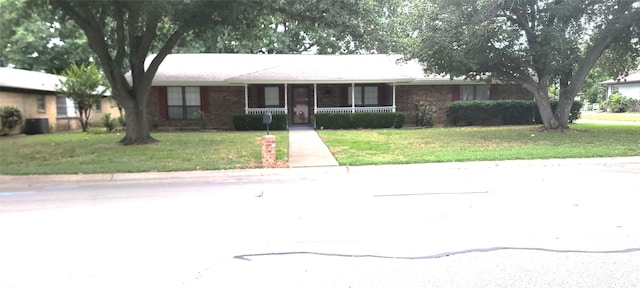 ranch-style home with brick siding, covered porch, and a front lawn