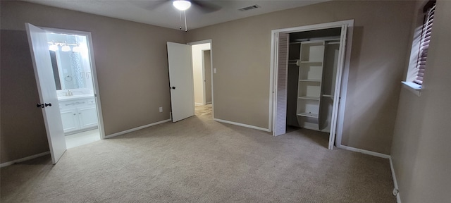 unfurnished bedroom featuring carpet flooring, a closet, ensuite bath, and ceiling fan