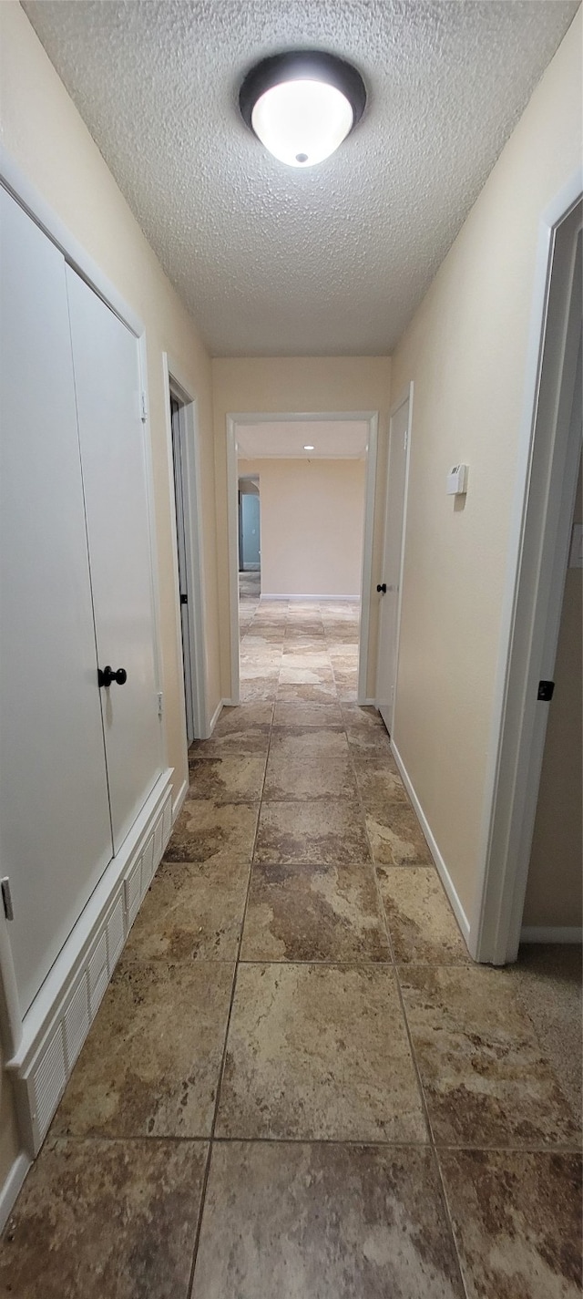 hall featuring tile patterned flooring and a textured ceiling