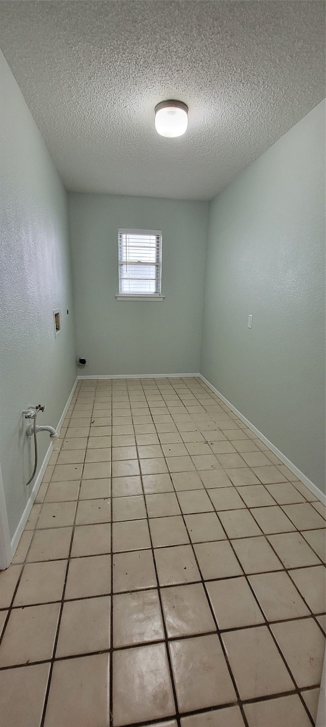 tiled empty room with a textured ceiling