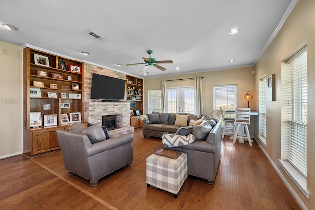 living room featuring wood-type flooring, built in shelves, french doors, ornamental molding, and ceiling fan