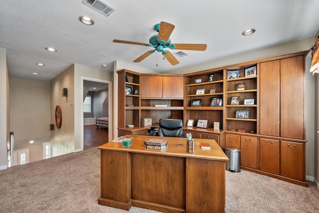 home office featuring ceiling fan, a textured ceiling, and light carpet