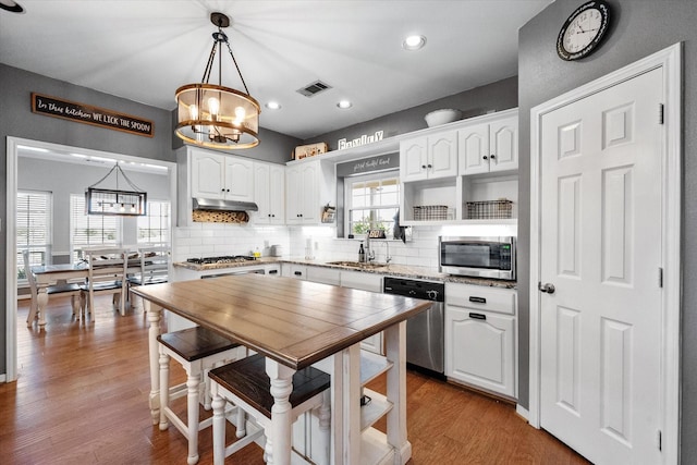 kitchen featuring sink, hanging light fixtures, white cabinets, and stainless steel appliances