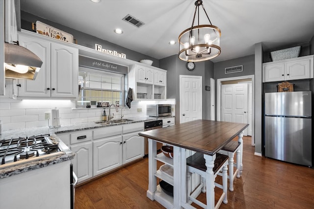 kitchen with backsplash, sink, white cabinetry, appliances with stainless steel finishes, and light stone counters