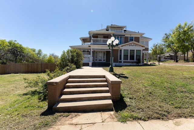 view of front of property featuring a balcony and a front yard