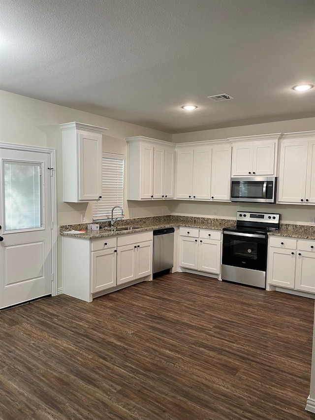 kitchen with a textured ceiling, white cabinets, dark wood-type flooring, stainless steel appliances, and sink