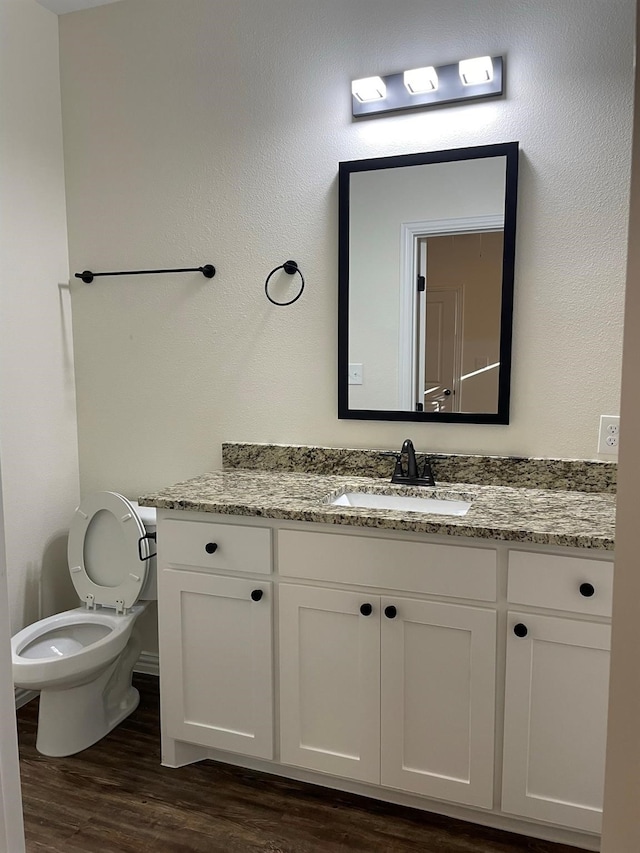 bathroom with wood-type flooring, toilet, and vanity