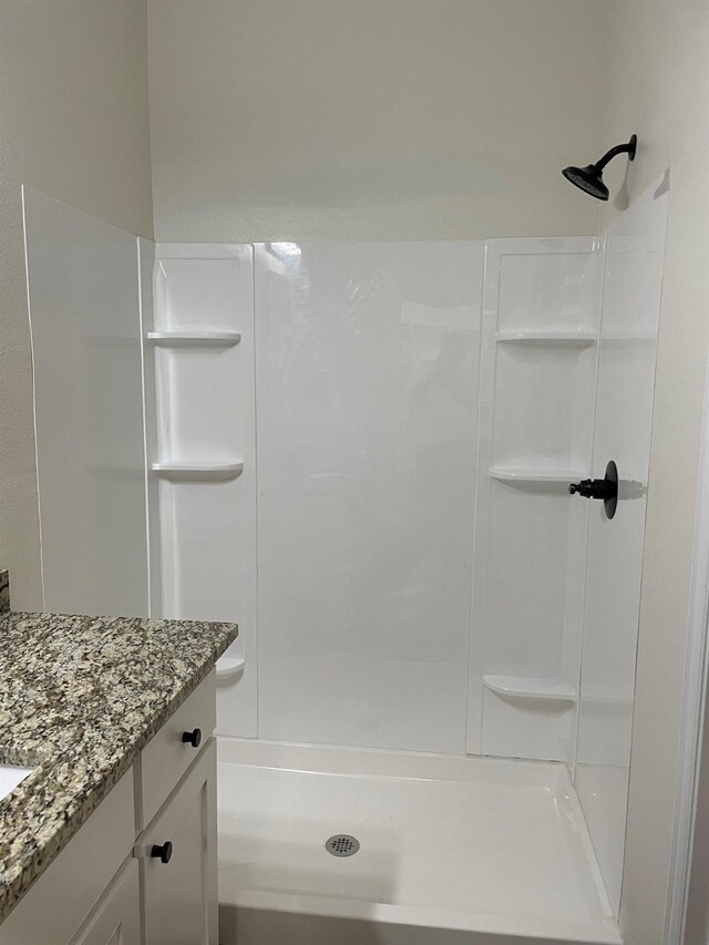 bathroom featuring walk in shower and vanity