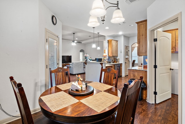 dining room with dark wood-type flooring and ceiling fan with notable chandelier