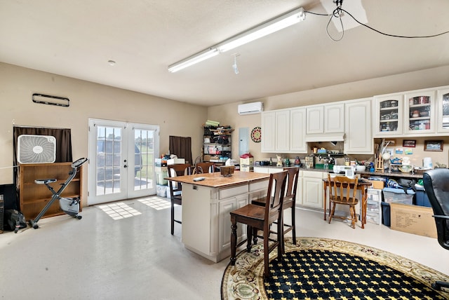 kitchen featuring a center island, white cabinetry, french doors, a kitchen breakfast bar, and a wall mounted AC