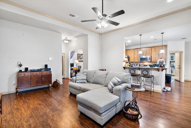 living room with ceiling fan, dark wood-type flooring, and crown molding