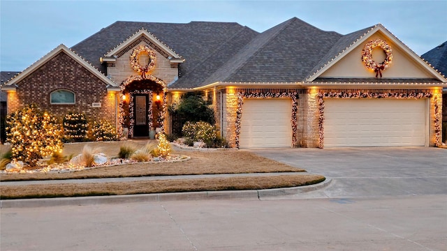 view of front of home with concrete driveway, brick siding, roof with shingles, and an attached garage