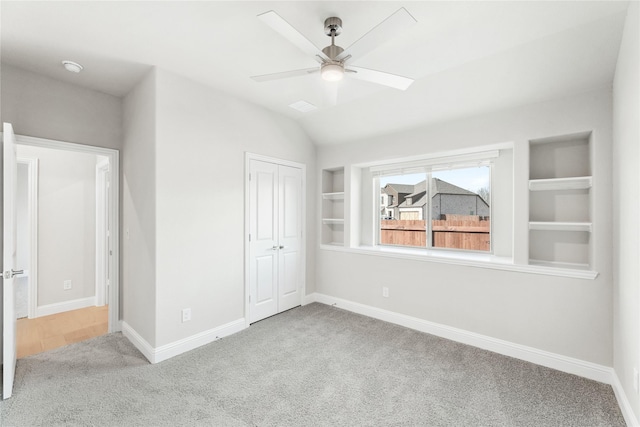 unfurnished bedroom featuring ceiling fan, light colored carpet, lofted ceiling, and a closet