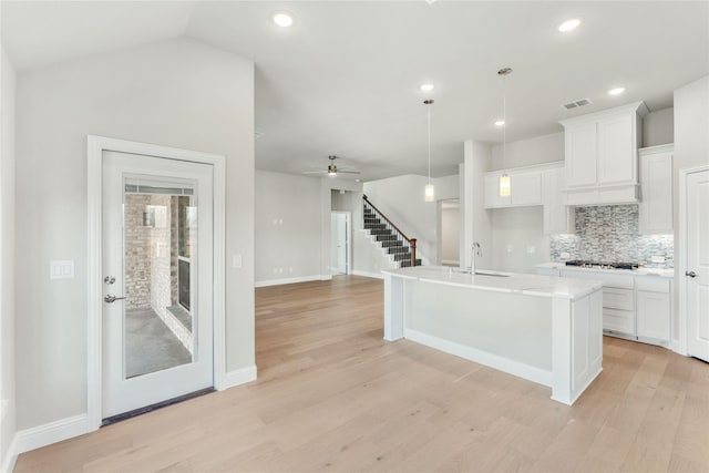 kitchen featuring hanging light fixtures, an island with sink, white cabinets, custom exhaust hood, and light wood-type flooring