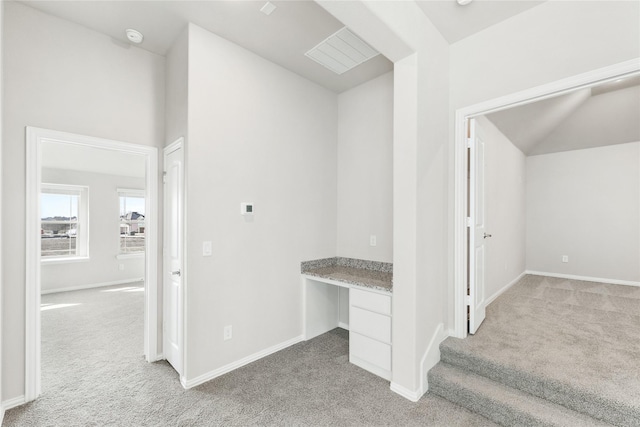 hall featuring light colored carpet and lofted ceiling