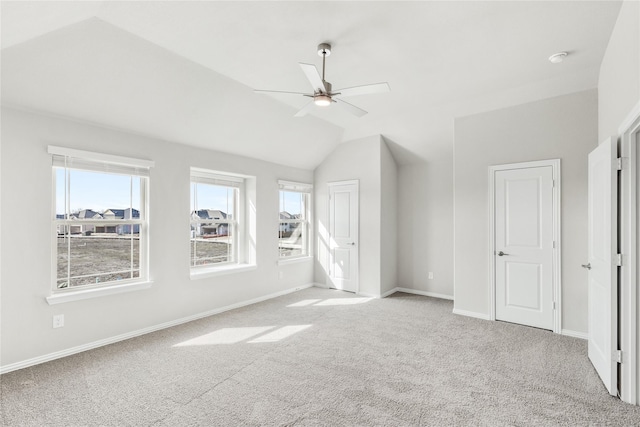 additional living space with ceiling fan, light colored carpet, lofted ceiling, and a wealth of natural light