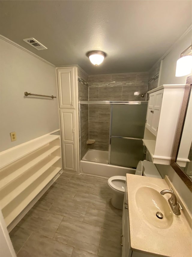 full bathroom with toilet, vanity, shower / bath combination with glass door, and ornamental molding