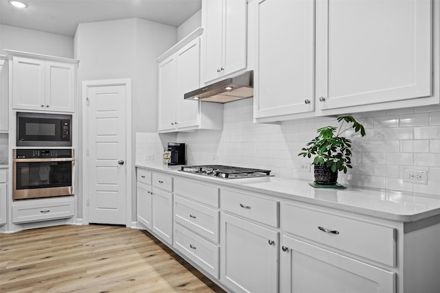 kitchen featuring under cabinet range hood, white cabinets, appliances with stainless steel finishes, and light countertops