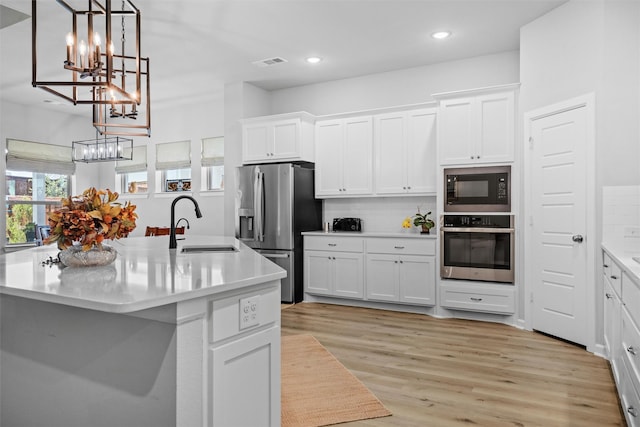 kitchen with white cabinetry, stainless steel appliances, and an island with sink