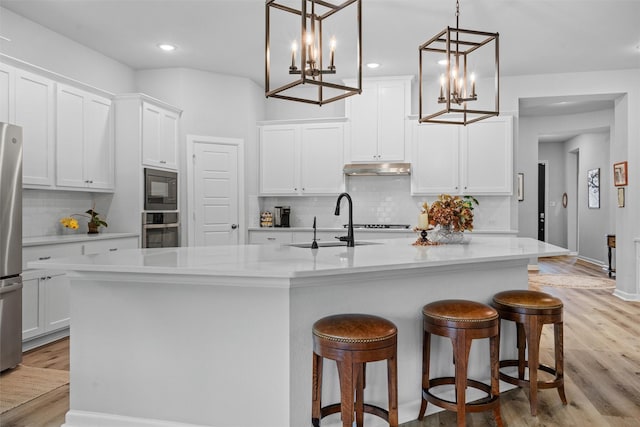 kitchen featuring pendant lighting, sink, a kitchen island with sink, stainless steel appliances, and white cabinets