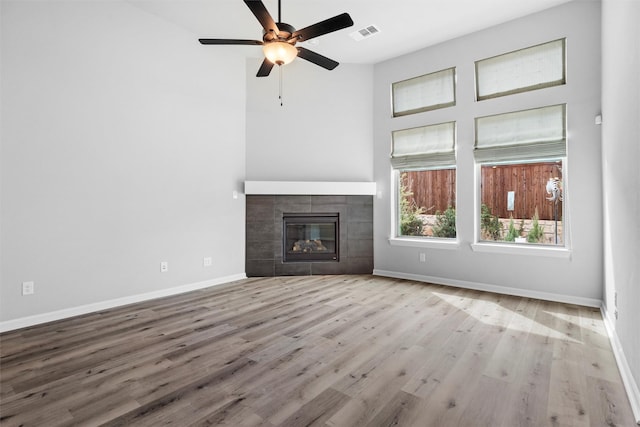 unfurnished living room featuring visible vents, baseboards, a fireplace, wood finished floors, and a ceiling fan