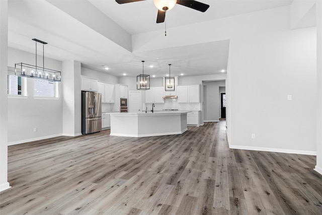 unfurnished living room with recessed lighting, light wood-style flooring, and baseboards