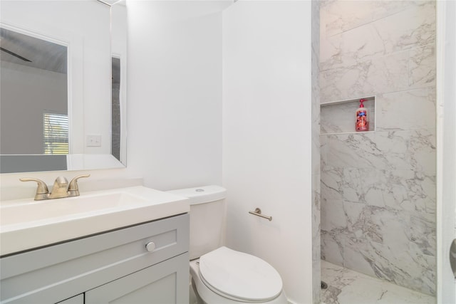 bathroom featuring a tile shower, vanity, and toilet