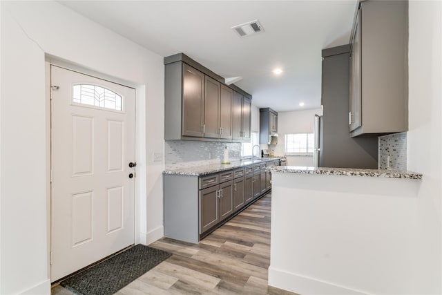 942 County Road 2240, Corsicana, TX 75109 - kitchen featuring gray cabinets, light wood finished floors, decorative backsplash, light stone counters, and plenty of natural light