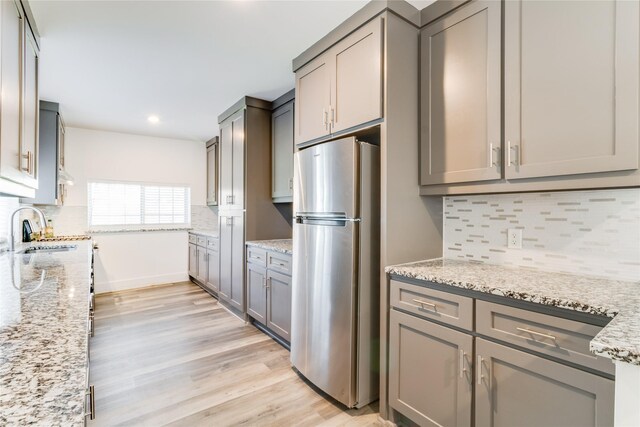 942 County Road 2240, Corsicana, TX 75109 - kitchen featuring freestanding refrigerator, a sink, decorative backsplash, light wood-type flooring, and gray cabinets