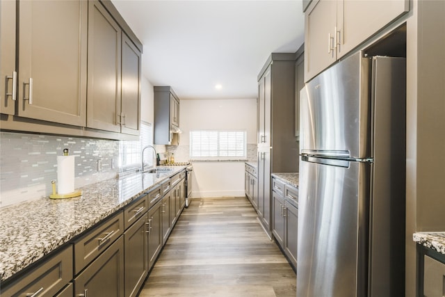 942 County Road 2240, Corsicana, TX 75109 - kitchen with freestanding refrigerator, a sink, light wood finished floors, decorative backsplash, and light stone counters
