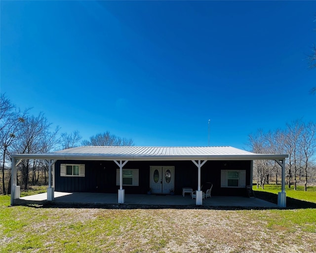 942 County Road 2240, Corsicana, TX 75109 - rear view of property featuring board and batten siding, metal roof, a patio area, and a lawn