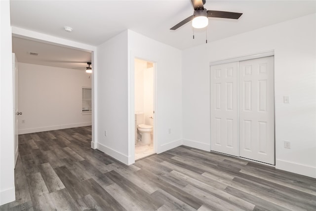 unfurnished bedroom with ceiling fan, dark hardwood / wood-style flooring, ensuite bath, and a closet