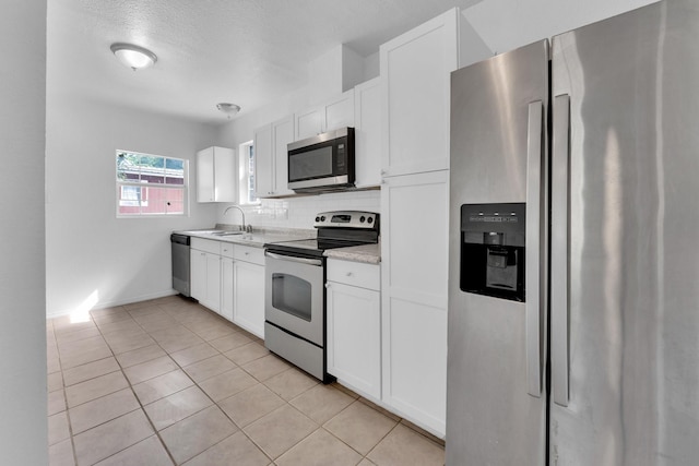 kitchen with white cabinets, light tile patterned flooring, sink, and stainless steel appliances