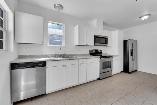 kitchen with backsplash, stainless steel appliances, sink, white cabinets, and light tile patterned flooring