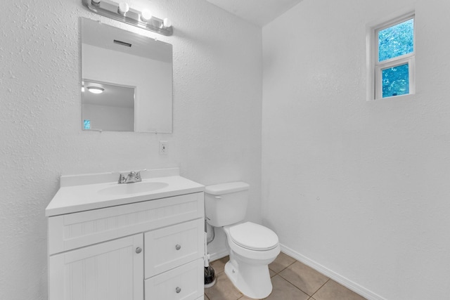 bathroom with toilet, vanity, and tile patterned floors