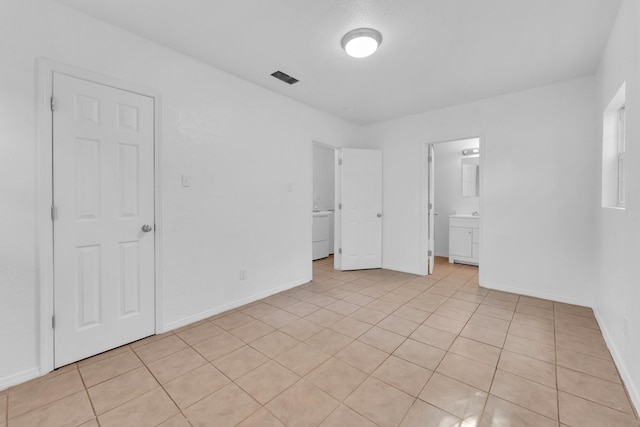 unfurnished bedroom featuring ensuite bathroom, a closet, and light tile patterned flooring