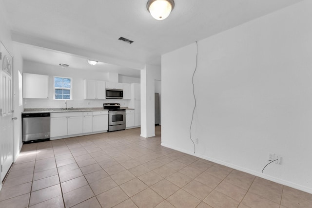 kitchen featuring white cabinetry, sink, light tile patterned floors, and appliances with stainless steel finishes